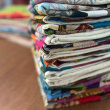 Load image into Gallery viewer, Stack of folded sari patchwork cushion covers on a brown wooden table