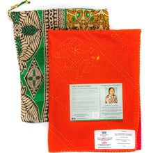 Load image into Gallery viewer, Orange fabric blanket with labels and a green and gold patterned bag on a white background
