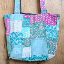 Load image into Gallery viewer, Patchwork tote bag with floral and paisley patterns on a wooden surface
