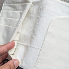 Load image into Gallery viewer, Close-up of a white fabric pocket with a hand holding it open on a grey background
