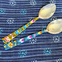 Load image into Gallery viewer, Two tablespoons with colourful painted handles on a blue patterned fabric background
