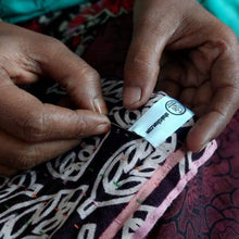 Load image into Gallery viewer, close-up shot of artisan&#39;s hands stitching saris together, shaktiism label applied
